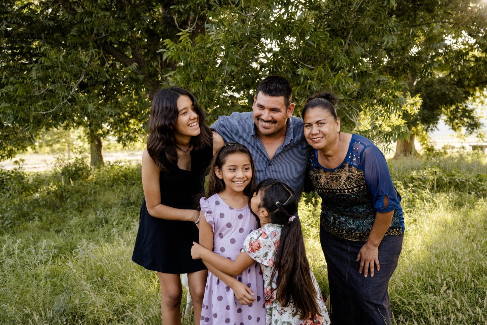 Una familia de Cuatro Ciénegas ríe abrazada bajo los árboles